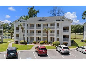 Three-story condo building featuring white exteriors, balconies, manicured landscaping, and convenient parking at 493 White River Dr. # 28-D, Myrtle Beach, SC 29579