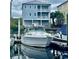 White boat docked at a marina, in front of a light blue three story house at 1316 Marina Bay Dr., North Myrtle Beach, SC 29582