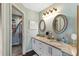 Bathroom featuring double sinks with granite countertop, oval mirrors, stylish light fixture, and tiled walk-in shower at 4396 Baldwin Ave. # 47, Little River, SC 29566