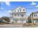 Inviting three-story white home with a double garage and charming balcony, set against a clear blue sky at 2401 Duffy St., North Myrtle Beach, SC 29582