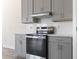 Close-up of a stainless steel stove set in gray cabinets with matching white backsplash and countertop at 2401 Duffy St., North Myrtle Beach, SC 29582