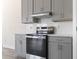 Close up of the kitchen with stainless steel appliances, gray cabinets, and subway tile backsplash at 2401 Duffy St., North Myrtle Beach, SC 29582