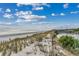 Scenic view of the beach from a dune, showcasing the sand, sea, and nearby community features at 5905 S Kings Hwy. # A 115, Myrtle Beach, SC 29575