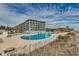 Large community pool and condo building surrounded by palm trees at 5905 S Kings Hwy. # A 115, Myrtle Beach, SC 29575