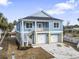 Two-story coastal home features a two-car garage, painted siding, and a charming second-story balcony at 2307 Tortuga Ln., North Myrtle Beach, SC 29582