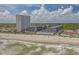 Aerial view showcases a high-rise condo complex with a sandy beach, pool, and picturesque coastline at 5905 S Kings Highway # 1117, Myrtle Beach, SC 29575
