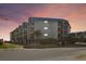 Exterior shot of a condo building with parking and multiple floors of balconies at sunset at 6000 N Ocean Blvd. # 131, North Myrtle Beach, SC 29582