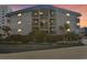 Night shot of a condo building with illuminated balconies surrounded by palm trees at 6000 N Ocean Blvd. # 131, North Myrtle Beach, SC 29582