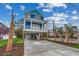 Stilt home features blue siding, white trim, and a covered parking area with palm trees at 721 10Th Ave. S, Surfside Beach, SC 29575