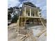 New construction home featuring a raised foundation and covered porch with classic column details under a partly cloudy sky at 723 10Th Ave. S, Surfside Beach, SC 29575