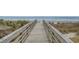 Wooden boardwalk leading to a sandy beach with palm trees and ocean views at 6804 N Ocean Blvd. # 1037, Myrtle Beach, SC 29572