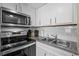Kitchen featuring stainless steel appliances, white cabinets, a double basin sink, and tile backsplash at 6804 N Ocean Blvd. # 1037, Myrtle Beach, SC 29572