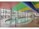 Indoor pool with large windows, lounge chairs and a colorful ceiling at 6804 N Ocean Blvd. # 1037, Myrtle Beach, SC 29572