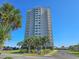 Exterior view of a high-rise condo building, landscaped grounds, and a blue sky backdrop at 9820 Queensway Blvd. # 501, Myrtle Beach, SC 29572