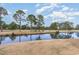 Picturesque golf course featuring a tranquil pond, lush green grass, and mature trees, ideal for scenic play at 4733 Wild Iris Dr. # 302, Myrtle Beach, SC 29577