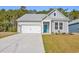 Charming single-story home featuring a bright blue door, gray siding, and a well-maintained front yard at 397 Sun Colony Blvd., Longs, SC 29568
