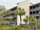 Exterior view of condo building with multiple units, palm trees, and neatly manicured grounds at 212 2Nd Ave. N # 362, North Myrtle Beach, SC 29582