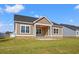 Tan siding and brick foundation, this home features a covered porch and lush lawn at 623 Carter Reid Ct., Longs, SC 29568