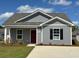 Charming single-story home featuring gray siding, a red front door, and a well-manicured lawn at 204 Cambridge Dr., Tabor City, NC 28463