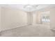 Bright, carpeted bedroom with neutral walls, a tray ceiling, and a large window overlooking the yard at 2513 Hunters Trail, Myrtle Beach, SC 29588