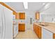 Well-lit kitchen featuring wood cabinets, white appliances, and tile flooring at 2513 Hunters Trail, Myrtle Beach, SC 29588