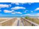 Beach boardwalk view leading to the sandy beach and ocean under a bright blue, cloudy sky at 1605 S Ocean Blvd. # 410, Myrtle Beach, SC 29577
