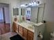 Bathroom vanity with double sinks, granite countertop, framed mirror, lighting, and tile floor at 144 Waterway Crossing Ct., Little River, SC 29566