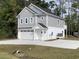 Side view of a two-story gray home with a garage and balcony, surrounded by lush greenery and a long driveway at 1738 Cenith Dr., North Myrtle Beach, SC 29582