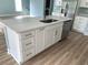 Close up view of kitchen island with stainless steel sink, white countertop, and soft-close drawers, and appliances at 1738 Cenith Dr., North Myrtle Beach, SC 29582