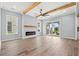 Bright living room features electric fireplace, hardwood floors, wood beams, ceiling fan, and sliding glass doors to backyard at 219 West Palms Dr., Myrtle Beach, SC 29579