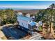Aerial view of a coastal home with a blue metal roof near the beach, marsh, and surrounding trees at 189 Brown Pelican Loop, Pawleys Island, SC 29585