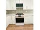 Close-up of modern kitchen with white cabinets, mosaic tile backsplash, and stainless steel gas range at 189 Brown Pelican Loop, Pawleys Island, SC 29585