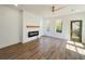Bright living room with wood floors, white shiplap accent wall with fireplace, modern fan, and natural light at 189 Brown Pelican Loop, Pawleys Island, SC 29585