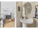 Chic powder room featuring a pedestal sink, decorative mirror, and views into a bright, modern kitchen at 4524 Landing Rd., Little River, SC 29566