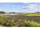 Lush marsh view with a boat dock and boats floating on the water under partly cloudy skies at 4524 Landing Rd., Little River, SC 29566