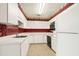 Kitchen with white cabinets, red floral wallpaper, and appliances at 1492 Fox Hollow Way, North Myrtle Beach, SC 29582