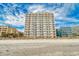 A full front view of a tall building sitting on the sandy beach on a sunny day at 1207 S Ocean Blvd. # 20808, Myrtle Beach, SC 29577