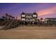 Beachfront home featuring multiple balconies, lush palm trees, and a walkway to the beach at 1907 S Waccamaw Dr., Garden City Beach, SC 29576