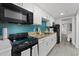 Efficient kitchen featuring white cabinets, black appliances, and blue backsplash at 7200 Ocean Blvd. N # 254, Myrtle Beach, SC 29572