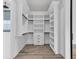 Walk-in closet with white built-in shelving and drawers, crown molding, and wood-look flooring at 835 Waterton Ave., Myrtle Beach, SC 29579