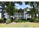 Exterior view of a three-story condominium with well-manicured landscaping and palm trees at 9550 Dunes Gable Dr. # F, Myrtle Beach, SC 29572