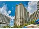 View of the tall condo building with many windows, balconies, and lush tropical landscaping at 9994 Beach Club Dr. # 205, Myrtle Beach, SC 29572