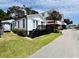 Charming white cottage with a black deck, enhanced by lush landscaping, offers curb appeal at 6001 - 5410 S Kings Hwy., Myrtle Beach, SC 29575