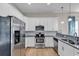 Galley kitchen features stainless steel appliances, white cabinets, and granite countertops at 4989 Salt Creek Ct., North Myrtle Beach, SC 29582