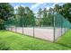 Outdoor tennis court surrounded by a green fence and trees at 7270 Guinevere Circle, Myrtle Beach, SC 29588