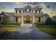 Stunning two-story white brick home with large columns and professionally landscaped front yard at twilight at 9318 Cove Dr., Myrtle Beach, SC 29572