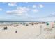 A wide, sandy beach features scattered beachgoers enjoying the sun, sand, and waves under a partly cloudy sky at 5905 S Kings Hwy. # 231, Myrtle Beach, SC 29577