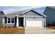 Charming single-Gathering home showcasing blue siding, a white garage door, and manicured landscaping at 572 Duvall St., Longs, SC 29568
