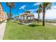 Outdoor picnic area with picnic tables under wooden pergolas, lush green grass, and palm trees at 6900 N Ocean Blvd. # 405, Myrtle Beach, SC 29572