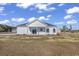 Back exterior of home with white siding, a dark roof, and a covered porch area on a sunny day at 107 Deans Ct., Green Sea, SC 29545